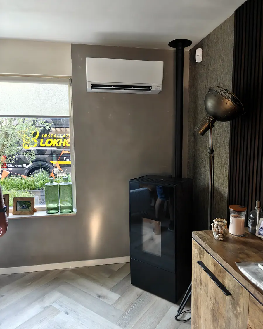 Binnendeel van een airco in een woonkamer met houtkachel en visgraatvloer