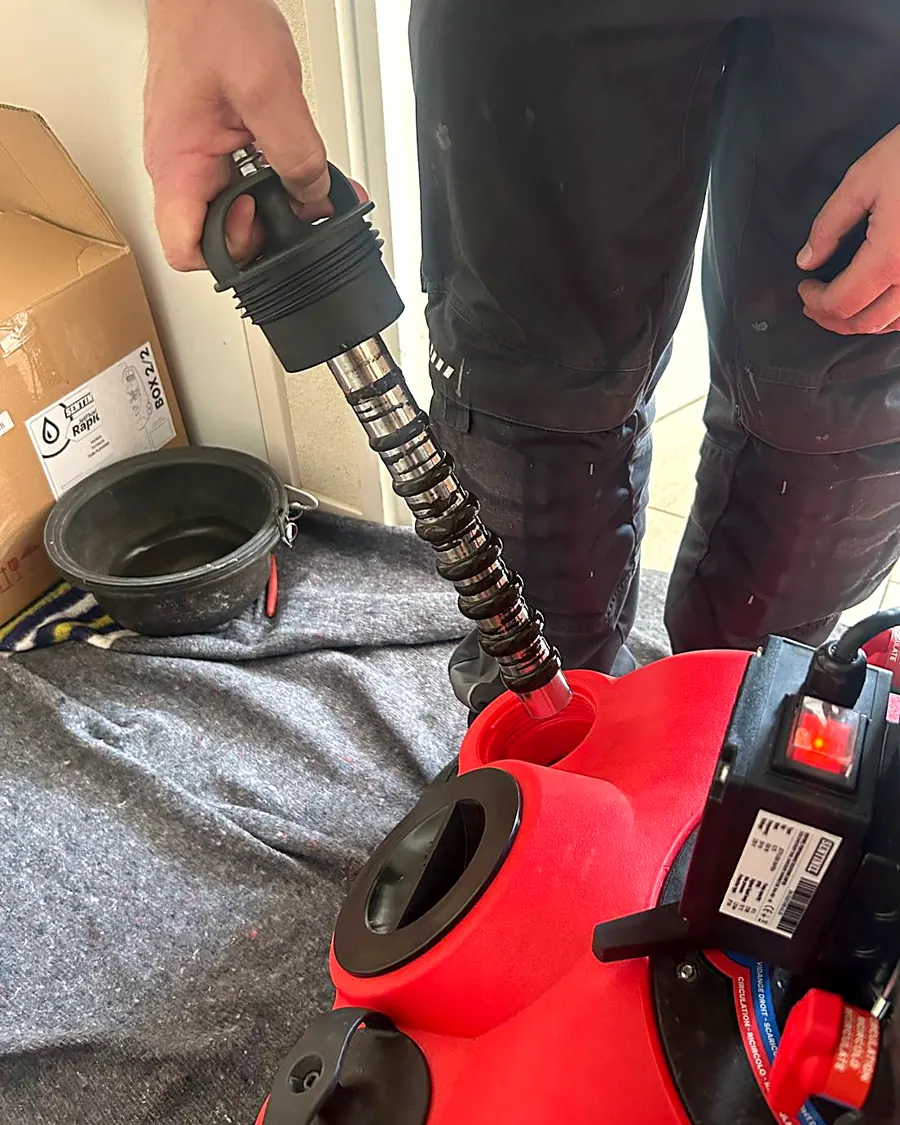 De magneetstaaf wordt uit de rode spoelmachine gehaald, vol zwart magnetiet uit de cv-installatie